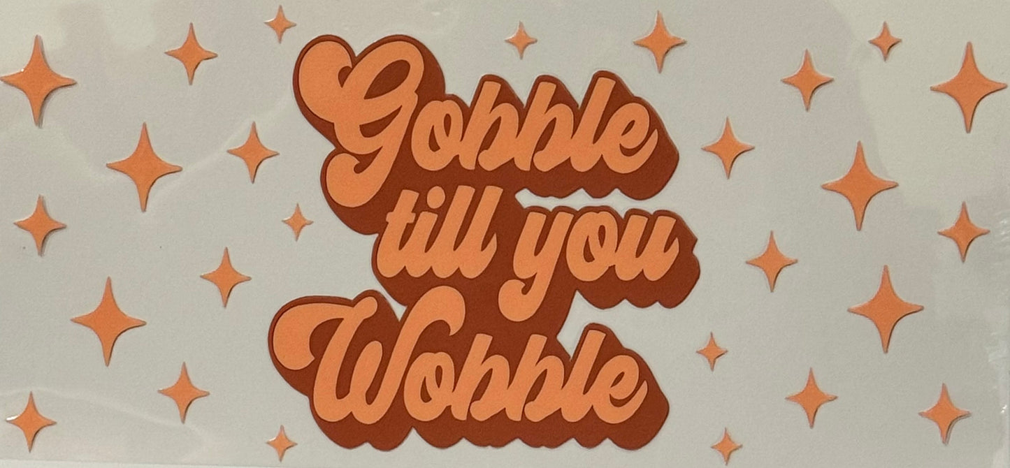 Orange retro-style text saying Gobble till you Wobble with sparkles around it.