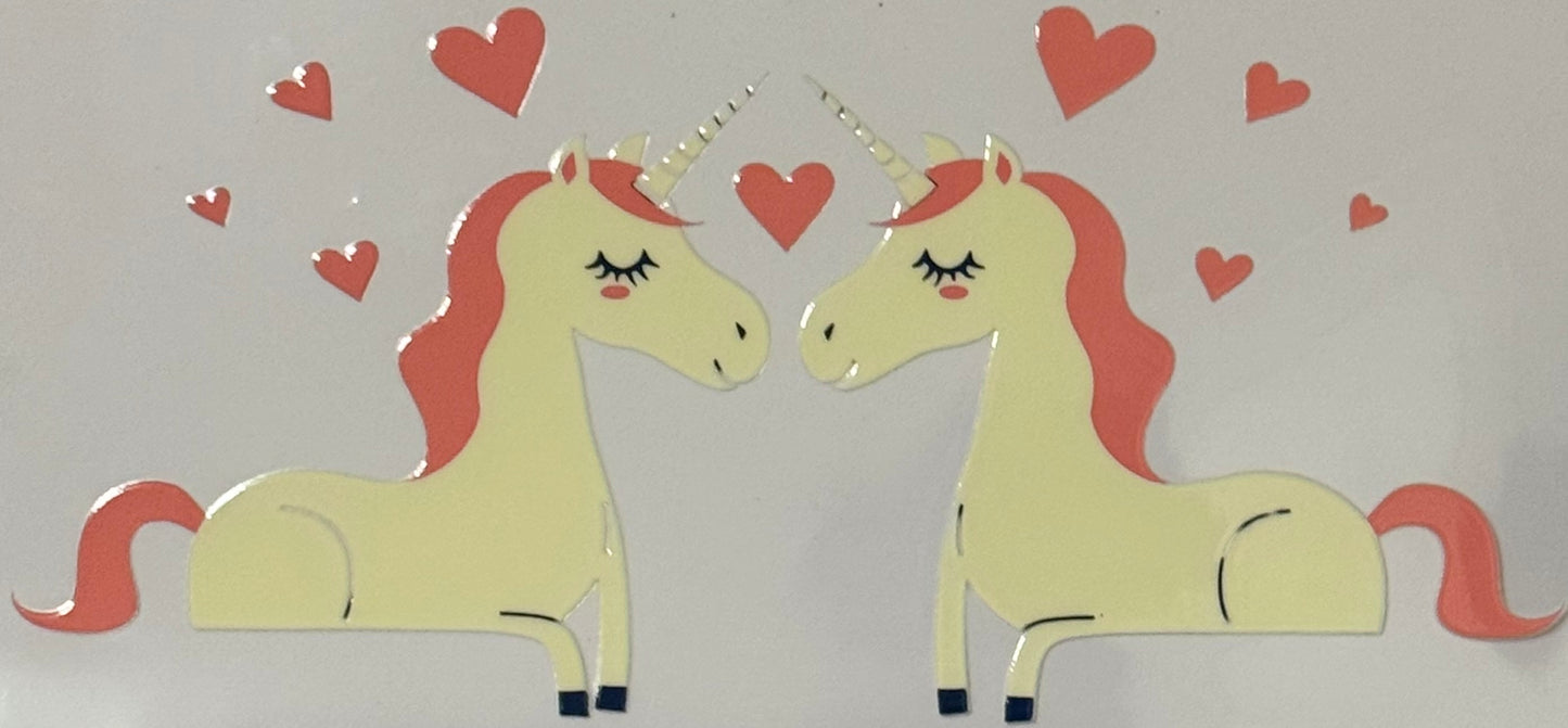 Two cream unicorns with coral manes surrounded by red hearts.