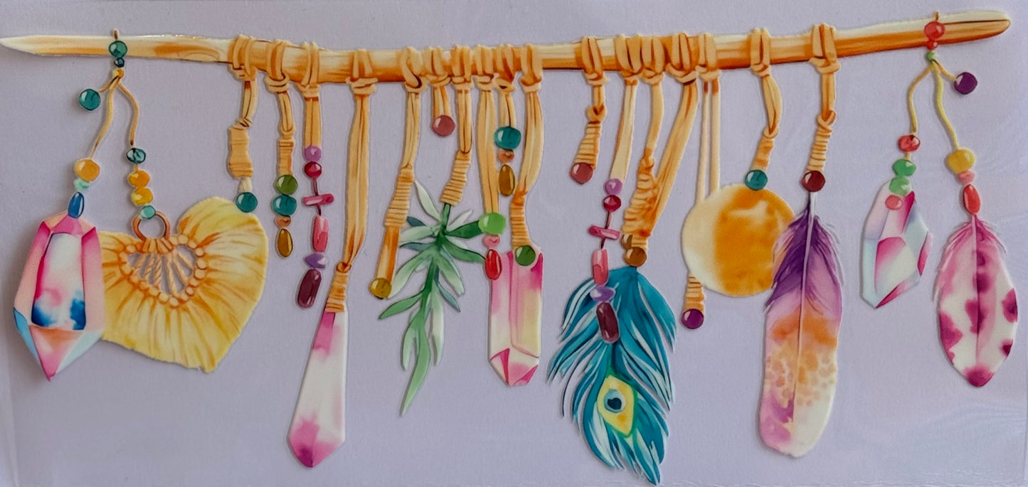 Boho DTF wrap featuring charms, crystals, feathers, and beads hanging from a wooden stick.