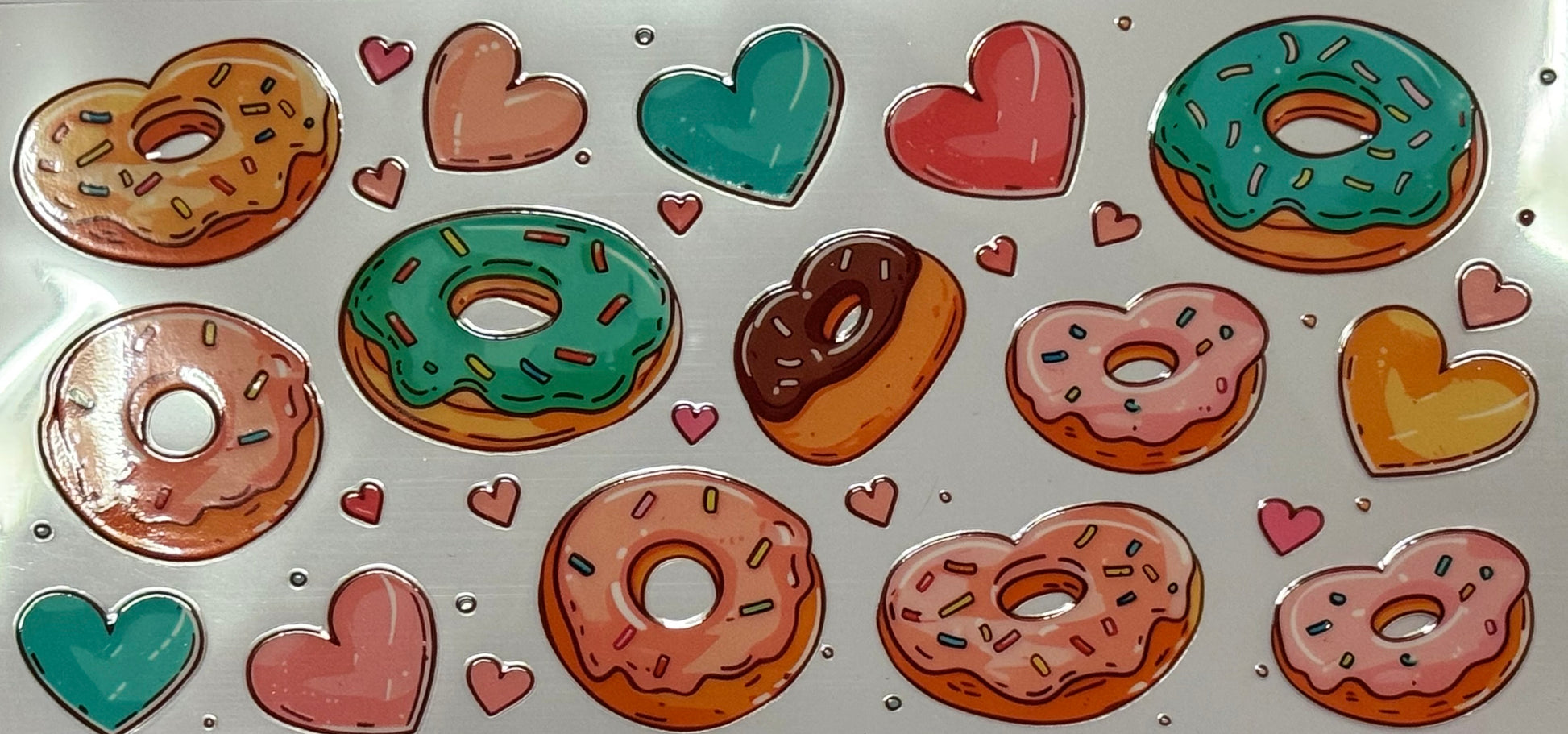 Pink, green, and chocolate donuts with sprinkles mixed with pink, teal, and yellow hearts.